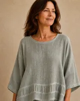 Blusa de lino color verde, de corte holgado, con escote redondo y mangas tres cuartos anchas. Presenta un detalle de frunce en el panel inferior.