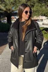 Campera de cuero negro con interior y detalles en cuello y puños de corderito sintético negro. Presenta cierre frontal con botones, bolsillos laterales y diseño de paneles horizontales.