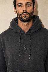 Hoodie de algodón color negro carbón con efecto garment washed, capucha con cordones ajustables y un sutil bordado en el pecho.