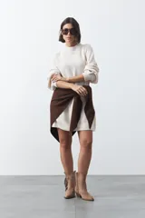 Vestido corto de punto en color beige, con cuello alto acanalado, mangas largas con puños ajustados y diseño holgado.