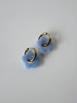 Aros de acero quirúrgico con argollas doradas y dije colgante en forma de flor color celeste.