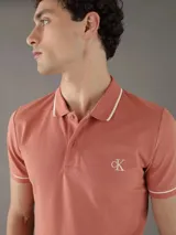 Chomba color salmón de corte slim fit, con cuello polo y mangas cortas con ribete blanco en contraste. Presenta logo CK bordado en el pecho. Confeccionada en mezcla de algodón y elastano.