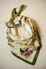 Pañuelo cuadrado de seda con estampado ilustrado de flora y fauna nativa del Uruguay, con borde en color verde.