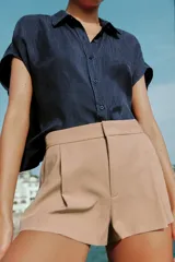 Shorts de tiro medio con bolsillos laterales y detalle de pinzas delanteras. Cierre frontal con cremallera, botón interior y gancho metálico.