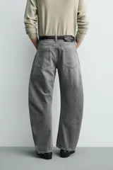 Jeans de denim de algodón en color negro con efecto lavado, corte amplio y silueta curva tipo barrel fit con pinzas en las rodillas. Presenta diseño clásico de cinco bolsillos y cierre frontal con cremallera y botón metálico.