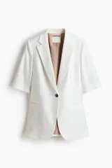 Blazer de botonadura sencilla con solapas de muesca, color blanco, de manga corta, con cierre de un botón y bolsillos delanteros ribeteados, con forro interno en tono tostado.