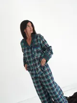 Pijama de franela a cuadros con estampado tartán, compuesto por una camisa de manga larga con solapas, bolsillo frontal y botones, y un pantalón largo de corte recto con puños y detalles en verde.