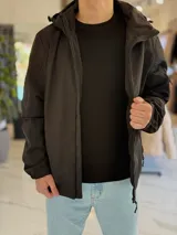 Campera 2 en 1 impermeable de color negro, con diseño con capucha y cierre frontal completo.