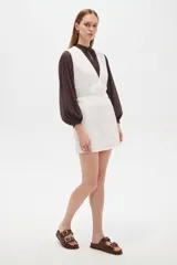 Falda mini blanca de algodón con diseño bordado y detalles fruncidos, de tiro alto y corte recto.