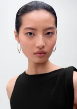 Vestido corto negro sin mangas, confeccionado en punto fino, con cuello barco y tirantes asimétricos.