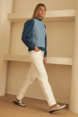 Chaleco de tejido de punto color marrón oscuro, con diseño de ochos y rombos en relieve. Tiene cuello redondo y es sin mangas.