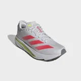 Championes de running Adidas Adizero SL2, diseñados con un exterior de malla técnica blanca y las icónicas tres tiras en color rosado. Incorporan tecnología de amortiguación Lightstrike Pro en la mediasuela con detalles en amarillo neón y suela de caucho para mayor tracción.