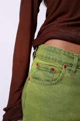 Jean de corte wide leg en color verde lima, con diseño de tiro medio, cinco bolsillos y cierre frontal con botón y cremallera.
