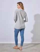 Buzo gris de tejido labrado, con cuello volcado y ruedo con terminaciones fruncidas regulables con lazo.