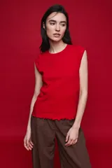 Remera sin mangas de silueta entallada, confeccionada en algodón elastizado con textura acanalada color rojo. Presenta escote redondo, terminaciones al tono y ruedo ondulado.