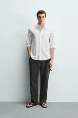 Camisa de corte regular fit color blanco, confeccionada en tejido de algodón con efecto arrugado, con cuello solapa, manga larga, puños abotonados y un bolsillo de parche en el pecho.