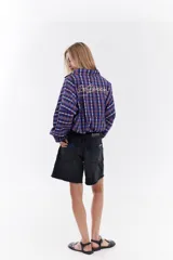 Chaqueta bomber de algodón con estampado a cuadros en tonos azules, amarillos y marrones, cuello alto y cierre frontal descentrado con botones. Cuenta con mangas abullonadas y puños elásticos.