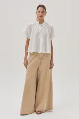 Blusa blanca de algodón con detalle metalizado, cuello con punto smock y mangas raglán.