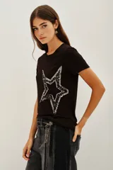 Remera negra de viscosa con cuello redondo y manga corta, presenta una estampa central de estrella grande decorada con lentejuelas brillantes.