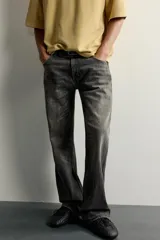 Jeans flare fit de denim de algodón en color gris con efecto lavado. Presentan diseño de cinco bolsillos, tiro medio y cierre frontal con cremallera y botón.