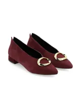 Zapato de punta fina en nobuck color bordeaux, con taco bajo y aplique metálico dorado en el empeine.