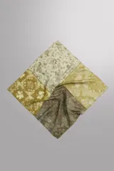 Bandana cuadrada confeccionada en tejido ligero de mezcla de ramio y algodón, con diseño de patchwork que combina paneles con estampados florales y paisley en tonos amarillo, mostaza y verde militar.