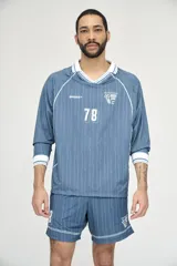 Camiseta de fútbol celeste con rayas verticales, cuello polo y mangas 3/4 con puños blancos. Incluye el número 78 en el frente y logos estampados.