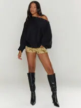 Sweater color crema con cuello asimétrico que puede usarse como escote off-shoulder, con botones a presión decorativos en el cuello y mangas abullonadas con puños acanalados.