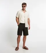 Bermuda de sarga color negro, de corte recto y diseño básico con bolsillos laterales y traseros.