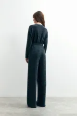 Mono largo de punto color gris oscuro con lurex, escote en V y cierre frontal con un botón. El pantalón es de corte palazzo.
