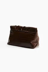 Clutch grande color marrón con textura de piel de cocodrilo, solapa con cierre magnético oculto y correa ajustable con hebilla de metal.