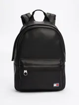 Mochila negra de poliuretano con acabado liso y diseño curvo. Tiene un compartimento principal con cierre de cremallera oculta, asa superior, correas ajustables y acolchadas, bolsillo interior de malla y bolsillo exterior con cremallera. Incluye inscripción de Tommy Jeans en las tiras e insignia de Tommy en la parte delantera.