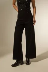 Pantalon de jean negro de corte ancho y tiro alto, con costuras verticales frontales y bolsillos laterales.