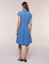 Vestido camisero corto de lyocell en tono azul denim, con cuello camisero, escote en V y cierre frontal con botones. Presenta mangas cortas, cintura entallada con pinzas verticales y falda evasé con vuelo.