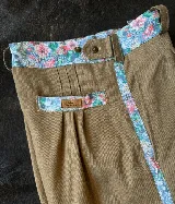 Bombacha de campo color beige con detalles de tela estampada floral en la pretina, bolsillos y franja lateral.