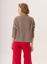 Buzo de lana color beige con cuello chimenea, mangas largas y diseño de tejido trenzado en la parte inferior y puños.