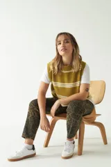 Chaleco de punto color ocre con rayas horizontales blancas, cuello redondo y sisas amplias.