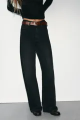 Jeans de mezclilla en color negro gastado, tiro alto, diseño de cinco bolsillos y corte de pierna ancha extra larga. Cuenta con cierre frontal de cremallera y botón metálico.
