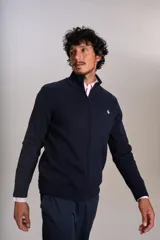 Cardigan de punto color azul marino, con cuello alto, cierre frontal completo y puños acanalados. Presenta el logo de la marca bordado en el pecho.