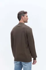 Campera de tejido de punto liviano color beige, con cierre frontal completo y cuello alto tipo bomber. Presenta un pequeño logo bordado en el pecho y puños acanalados.