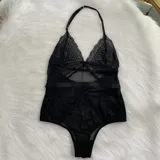 Body de encaje y microtul negro con diseño de escote halter, espalda descubierta y cierre con ganchos. Presenta paneles de encaje floral y secciones de tul transparente.