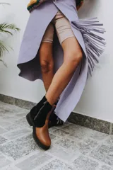 Botas de cuero marrón con la caña recubierta de corderito verde. Presentan una suela de plataforma tipo track en color beige y un tirador en la parte posterior para facilitar el calce.