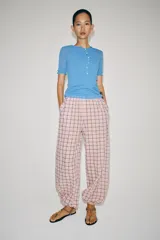 Pantalón bombacho de tiro medio, confeccionado en mezcla de algodón con estampado de cuadros en tonos rosados y oscuros. Presenta cintura elástica y bajo abullonado con puño elástico.