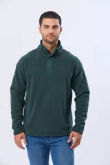 Buzo de abrigo confeccionado en tejido polar térmico, diseñado para mantener el calor y ofrecer resistencia al viento. Presenta un cuello alto con cierre frontal de broches, bolsillos laterales con cierre y un bolsillo adicional con cierre en la manga izquierda.