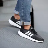 Championes adidas Swift Run de diseño urbano, confeccionados en tejido knit transpirable de color negro con las icónicas tres bandas laterales en blanco. Presentan una suela de espuma blanca con diseño esculpido y refuerzo en el talón.