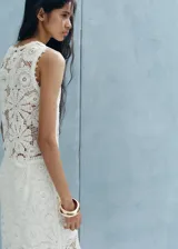 Top de encaje color blanco, sin mangas, con cuello redondo y diseño recto con detalles bordados calados.