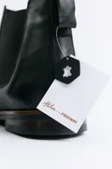 Bota tipo Chelsea de cuero negro con paneles elásticos laterales, suela de goma con detalle de vira en contraste y tirador trasero.