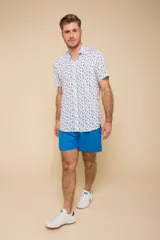 Camisa celeste con estampado floral blanco, de manga corta y corte clásico. Cierre frontal con botones.