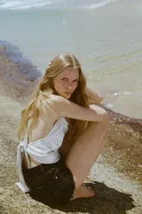 Short de jean negro desgastado, tiro alto, con roturas pronunciadas y terminación deshilachada en el bajo. Presenta cinco bolsillos y cierre frontal con botón metálico.