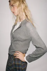 Chaqueta de punto gris con mezcla de lana, cuello redondo y manga larga. Cierre frontal con botones nacarados.